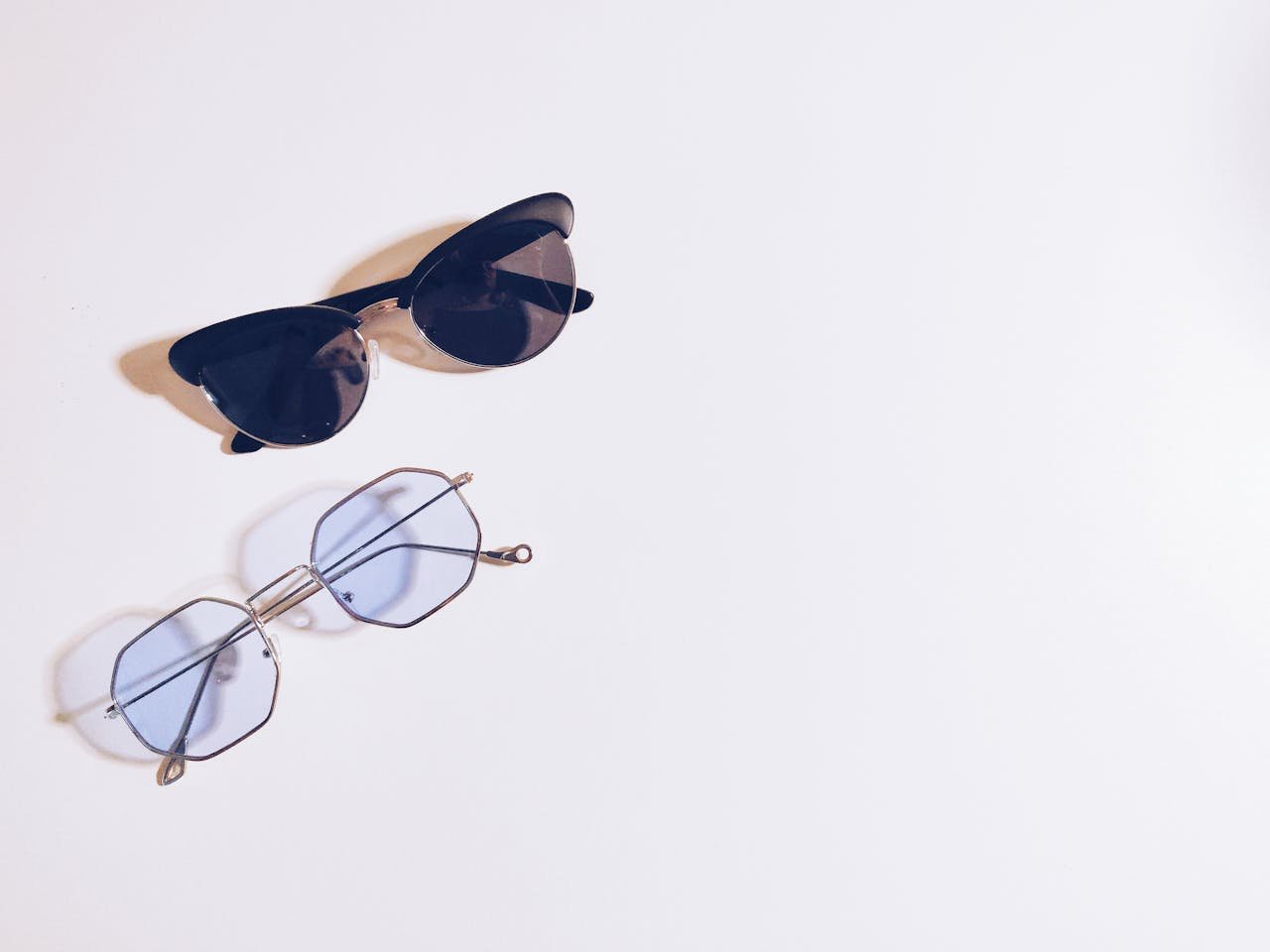 hero-img-02 Flat lay of sunglasses and eyeglasses on a white background, perfect for fashion design concepts.