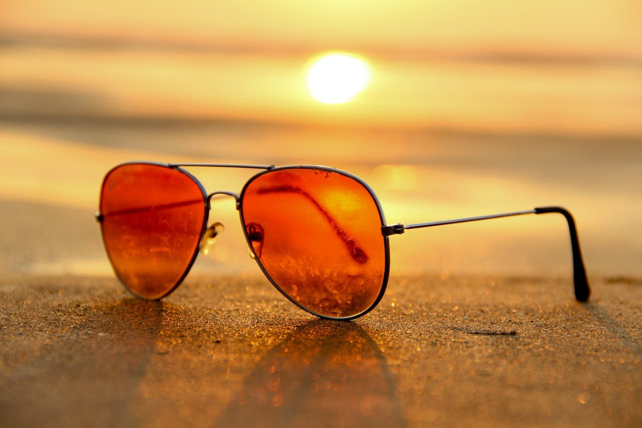 our-services-1 Close-up of sunglasses on a beach during a vibrant sunset, capturing the essence of summer.