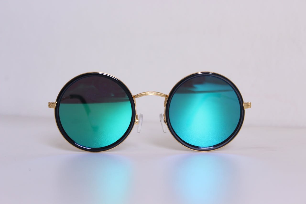 about-01 Elegant round sunglasses with blue-tinted lenses and gold frames, perfect for a trendy fashion statement.
